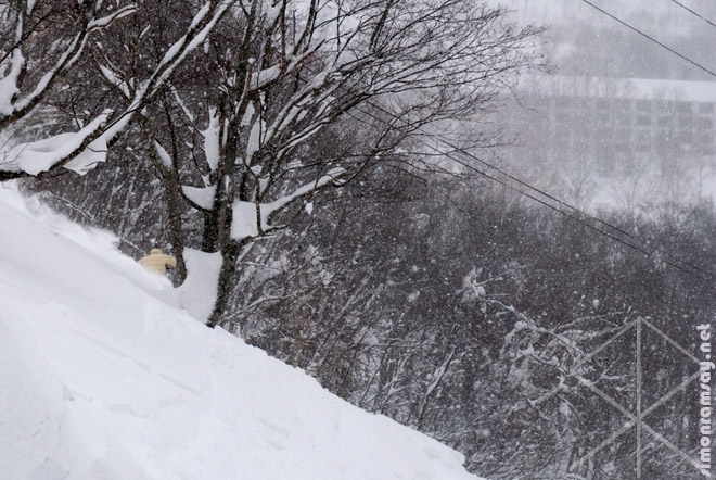 Skiing in the trees looking at the Green Leaf Hotel at Niseko Village